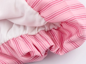 Dettaglio di camicia a righe rosa e bianche con orlo elastico e trama del tessuto