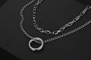 Close-up of double-layered silver chain necklace with paperclip links and ring pendant