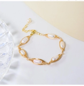Detailed macro view of handmade gold wire wrapped bracelet with natural white pearls
