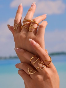 Close-up of gold stacking rings with moon and star motifs against a beach backdrop