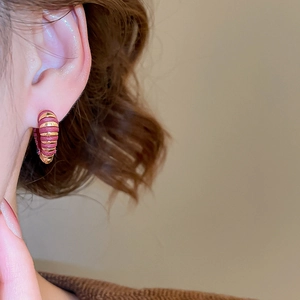 Détail rapproché de la boucle d'oreille cœur en or 18k avec rayures laque rouge vin