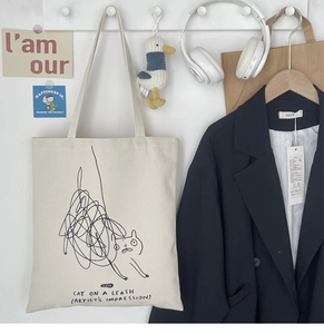 Detail of canvas tote bag featuring cute doodle cat print and Task Cat text on wall hook