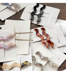 Macro detail of wavy acetate hair clips with marble textures on fashion jewelry cards