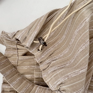 Detailed macro view of khaki striped fabric with elastic waistband and drawstring buckle