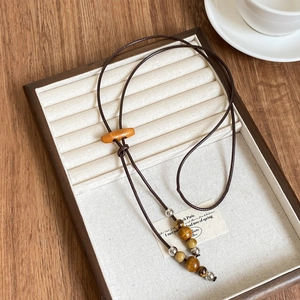 Détail du collier ethnique avec perles en œil de tigre, bois et cordon en cuir ciré marron