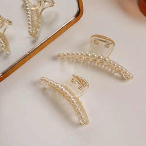 Close-up of champagne pearl hair claw clips on a beige surface with soft mirror reflection
