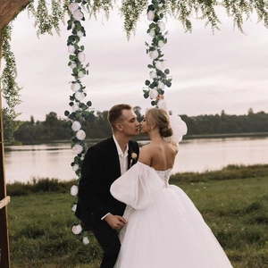 Wedding arch decor featuring white peonies and green eucalyptus vines by a lake