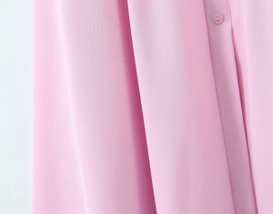 Vista macro dettagliata della trama del tessuto rosa con bottone e superficie liscia