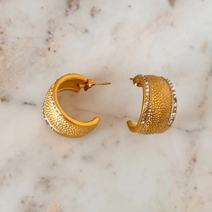 Detail of gold hammer textured C-shape hoop earrings with sparkling zircon accents