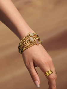Close-up of gold Cuban chain bracelets with zircon charms and embossed star signet ring