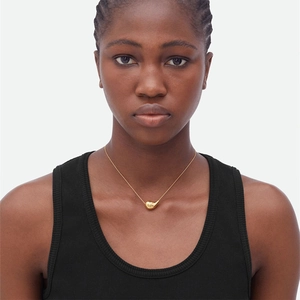 Polished gold teardrop pendant necklace on model with minimalist stainless steel chain