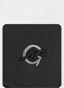 Detail of premium silver MG embroidery on black knit baseball cap with dense stitching