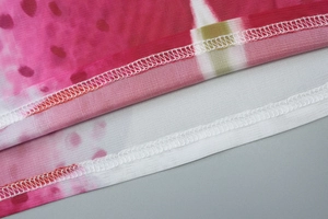 Détail du tissu en maille rose avec imprimé floral et couture précise sur l'ourlet