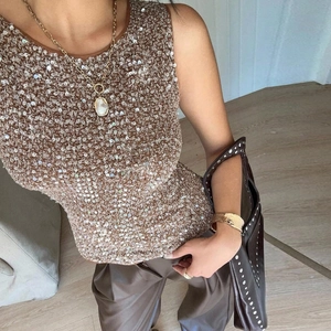 Détail du débardeur à paillettes dorées avec pantalon en similicuir marron et bijoux dorés