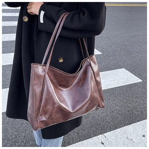Street style shot of a large brown leather tote bag paired with a black winter coat