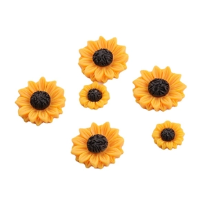 Flat lay of yellow resin daisy flower charms for DIY crafts in various sizes on white