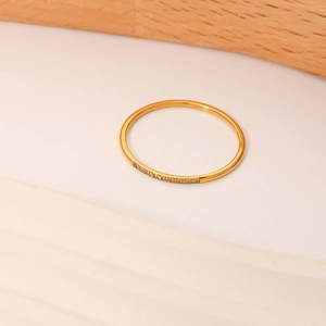 Minimalist 18K gold plated titanium steel ring with micro-set zircon stones on wood base