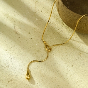 Détail d'une chaîne serpent dorée avec pendentif goutte sur un collier en Y élégant