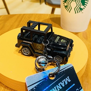 Detail of a black police car keychain with silver bell and patrol text on a yellow stand