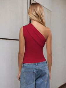 Rear view of a sexy red one-shoulder top paired with blue jeans against a neutral wall