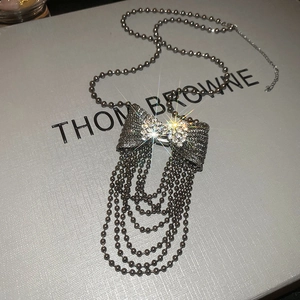 Macro view of sparkly rhinestone bow pendant with tiered silver ball chain tassels