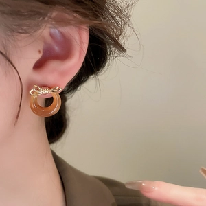 Close-up of golden bow earrings with amber resin hoop on model for vintage elegant look