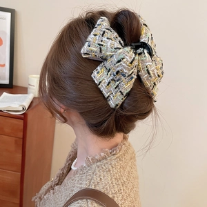Détail d'une grande pince à cheveux en tweed beige portée sur les cheveux