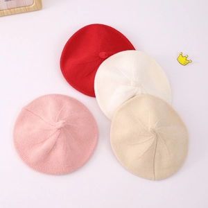 Flat lay of knit beret hats in red, pink, beige and brown with contrast bow details