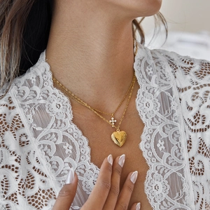 Close-up of a double-layered 18k gold plated necklace with heart and pearl cross pendants