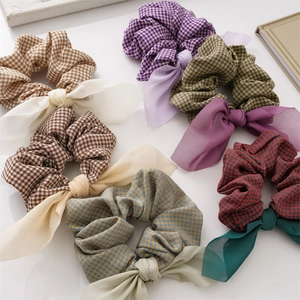 Flat lay of colorful plaid scrunchies with bow details on a white table background