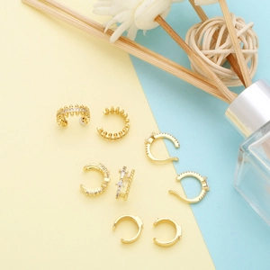 Macro shot of gold zircon ear cuffs set on a colorful minimalist artistic background