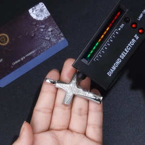 Moissanite cross pendant being tested with a diamond selector and GRA certificate