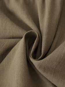 Macro shot of natural khaki linen fabric texture showing detailed weave and soft draping