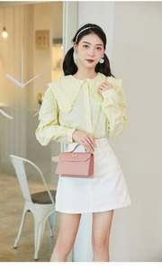 Pink flap crossbody bag with golden butterfly detail paired with a yellow ruffled shirt