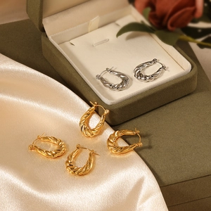 Twisted hoop earrings in gold and silver finish on a luxury velvet display case