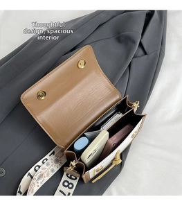 Interior view of dual-compartment crossbody bag with wide strap and metallic closure