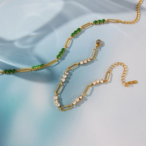 Detail of warm gold stainless steel bracelets with green and white zircon stones