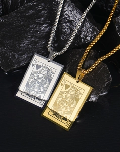 Detail of King of Hearts poker pendants in gold and silver finishes on a textured base