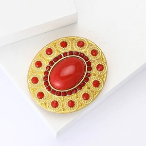 Vintage oval gold brooch with large red gemstone center on white pedestal display