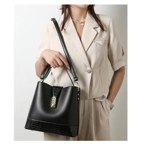 Detail of black bucket bag featuring crocodile embossed leather and gold twist lock closure