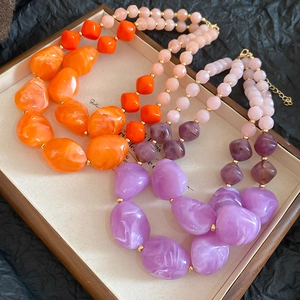 Macro shot of colorful irregular acrylic double-layered pendant necklaces in a wooden tray