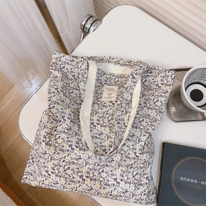 Detailed view of floral canvas tote bag with woven straps and decorative cloth label