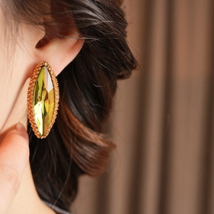 Macro shot of large olive green marquise stud earring with gold beaded metal frame