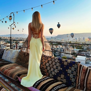 Détail d'une robe dos nu en soie jaune avec des lacets sur un balcon fleuri