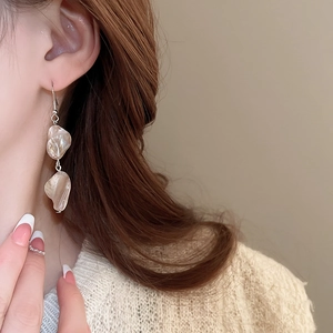 Dettaglio di eleganti orecchini a pendente in conchiglia beige con finitura lucida