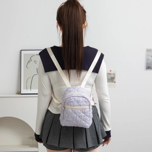 Detail of a purple plaid mini backpack with pink bow embroidery on a model’s back