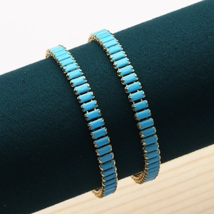 Detailed view of two 18K gold plated bracelets with turquoise stones on a display stand