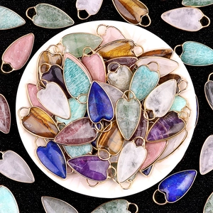 Assorted natural heart stone pendants with gold metal edge in a white ceramic dish