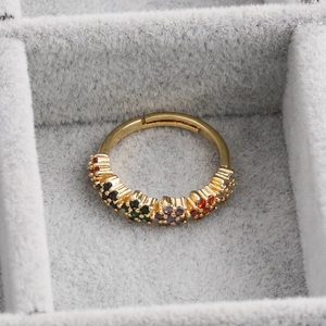Gros plan sur bague dorée ajustable avec cinq motifs floraux en zircons colorés sur velours