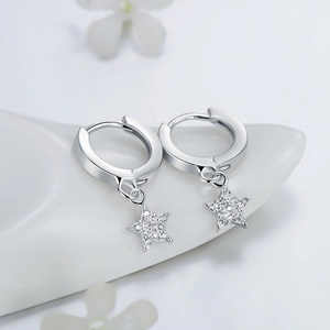 Sparkling S925 sterling silver star drop earrings displayed on a white ceramic tray
